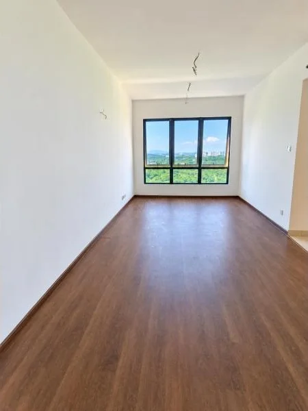 Room features: white painted walls, brown wood-look flooring, flat white ceiling, recessed ceiling wiring for light fixtures, large black-framed window, sliding window panels, natural daylight, long narrow room layout, baseboard trim, empty unfurnished room, view of greenery and distant buildings through window; style: modern; view: garden.