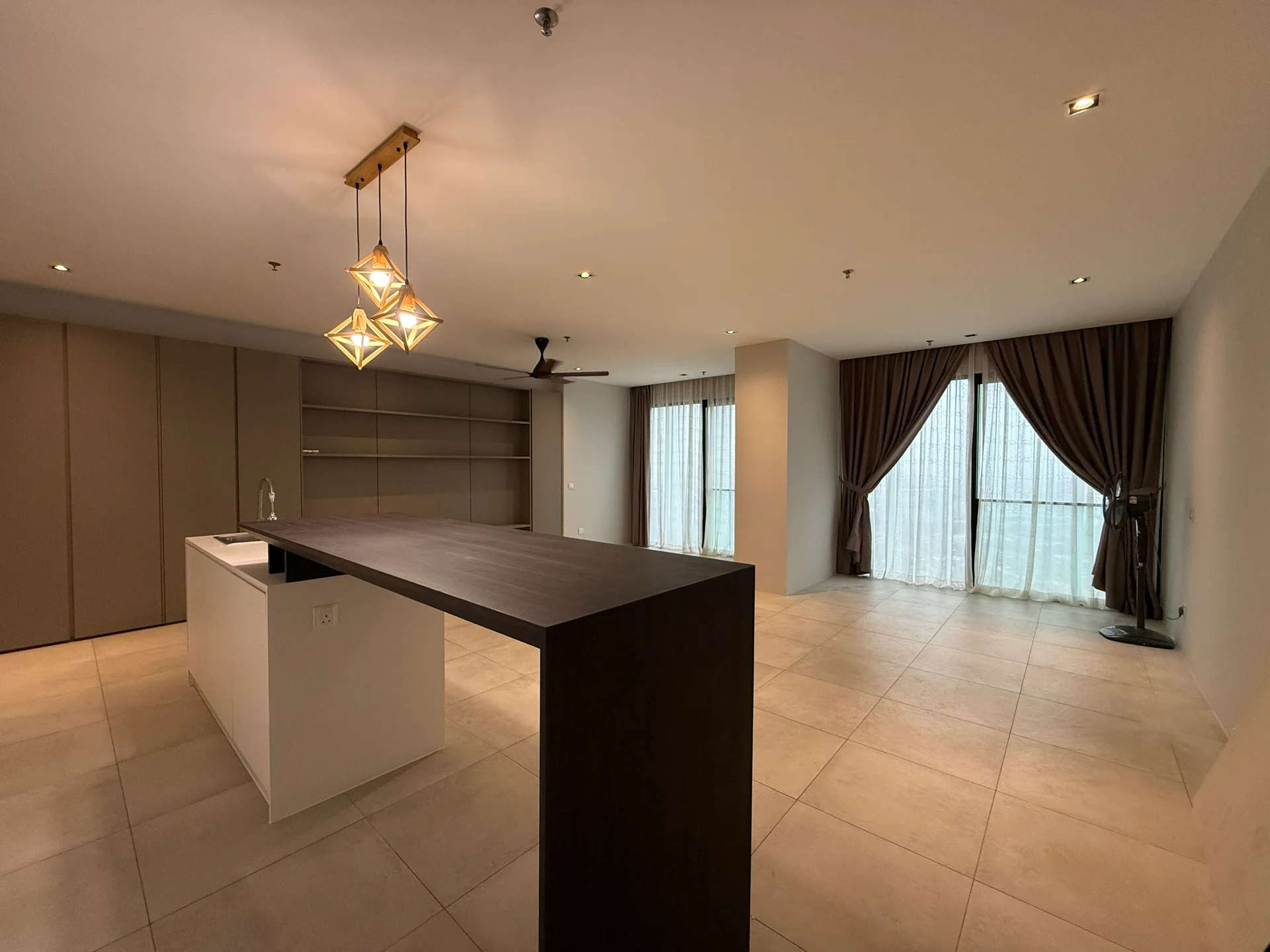 Living features: open-plan layout, large floor-to-ceiling windows, sheer curtains, dark wood island countertop, white cabinetry, recessed downlights, 5-blade ceiling fan with light, light beige tile flooring, decorative pendant lighting, built-in shelving, neutral painted walls; style: modern.