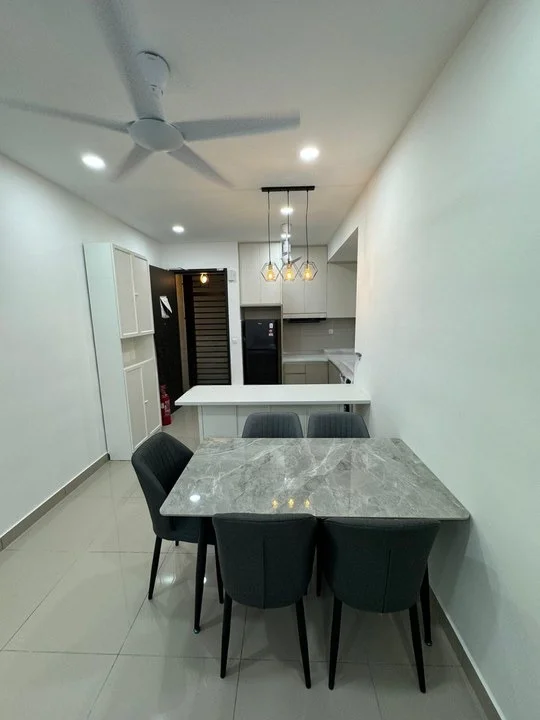 Dining features: 4-seater dining table with marble top, grey upholstered dining chairs, pendant light fixture with three bulbs, white painted walls, recessed LED downlights, ceiling fan, tile flooring, open kitchen layout visible in background; style: modern. Kitchen features: white cabinetry, built-in kitchen appliances, countertop with overhang for breakfast bar, grey backsplash, stainless-steel fridge visible; style: modern.