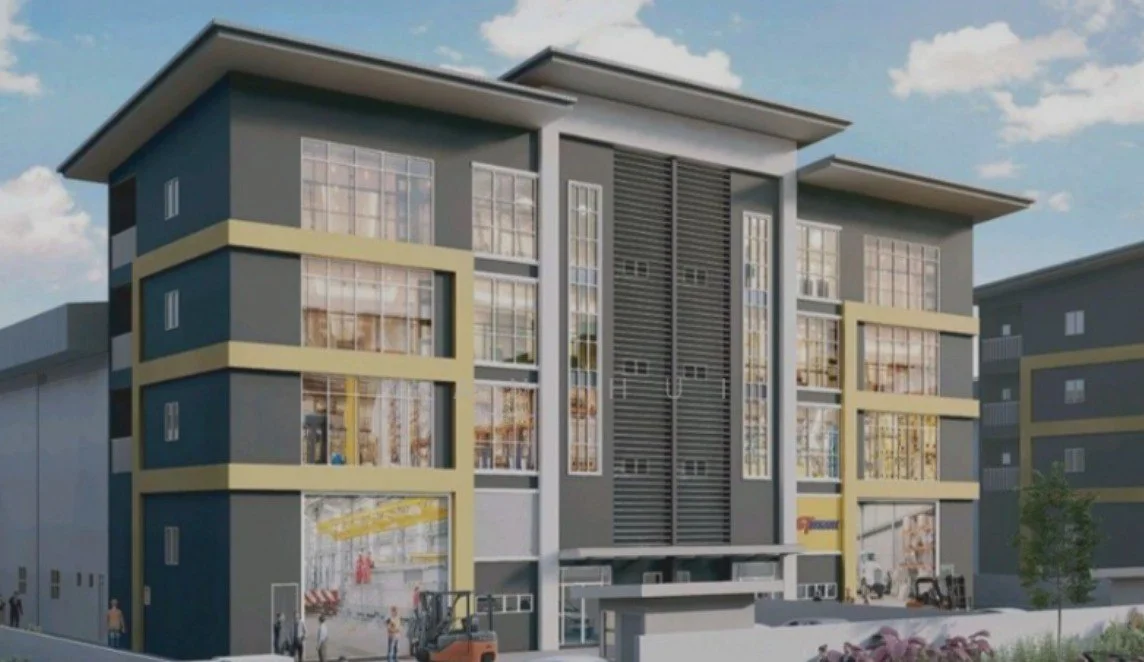 Exterior type: low-rise apartment block; features: grey painted facade, yellow accent stripes, large glass windows, horizontal louvre screens, flat roof, three-storey building, manicured landscaping, entrance with awning, loading area visible, surrounded by other buildings; style: modern.