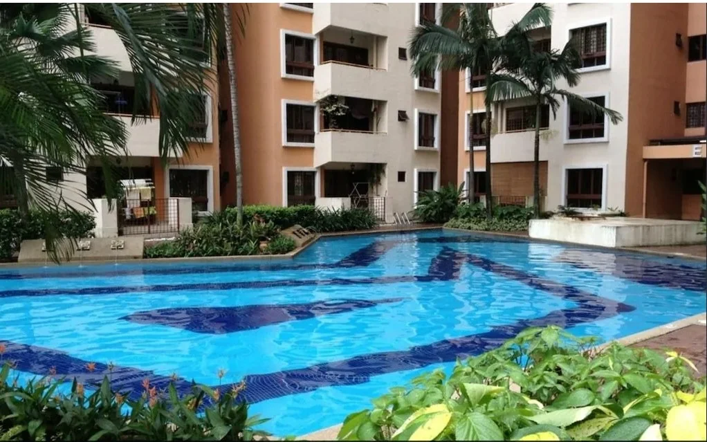 Exterior type: mid-rise condominium; features: swimming pool, landscaped garden, palm trees, manicured lawn, balconies on upper floors, glass railings, pool deck, surrounding greenery; style: modern.