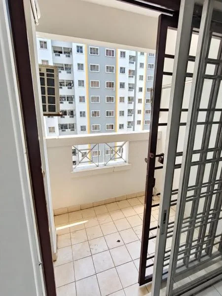 Balcony features: beige painted walls, beige ceramic tile flooring, sliding glass door, metal security grille door, half-height balcony wall, small rectangular balcony opening, metal balcony railing, view of adjacent apartment block, white exterior facade across courtyard, multiple windows on neighboring building, sunlight on floor, narrow balcony layout; style: contemporary; view: courtyard.