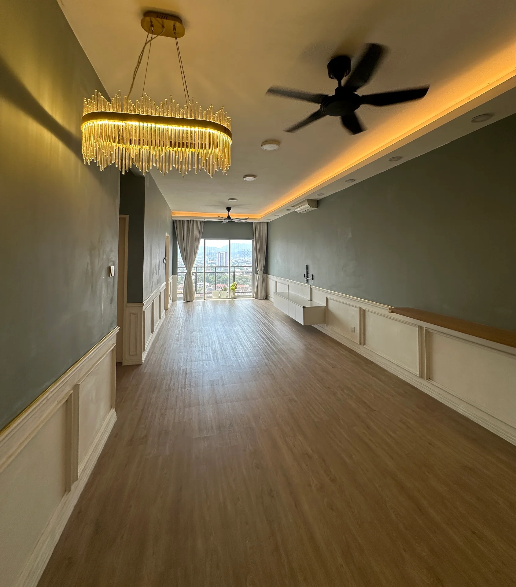 Living features: wooden flooring, green painted walls, crown moulding, chandelier with crystals, 5-blade ceiling fan, recessed downlights, floor-to-ceiling windows, curtains, balcony door, wall-mounted TV console, built-in cabinetry; style: modern; view: city.