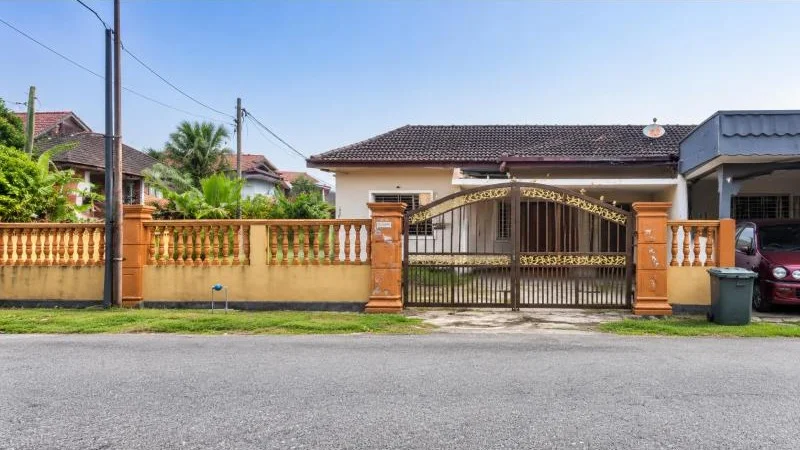 Exterior type: detached bungalow; features: single-storey, pitched tile roof, cream painted facade, orange boundary wall, ornamental balustrade fence, metal swing gate, covered car porch with awning, driveway entrance, fronts a quiet residential street, tropical landscaping, palm trees, mature greenery; style: traditional.