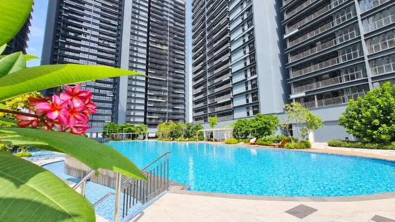 Exterior type: high-rise condominium; features: approximately 20-storey high-rise, glass and dark grey facade, recessed balconies, projecting balconies, multiple tower blocks, large outdoor swimming pool, pool deck with loungers, tropical landscaping, palm-like plants, manicured shrubs, stone-paved pool deck, metal pool handrail, surrounded by mature greenery; style: modern.