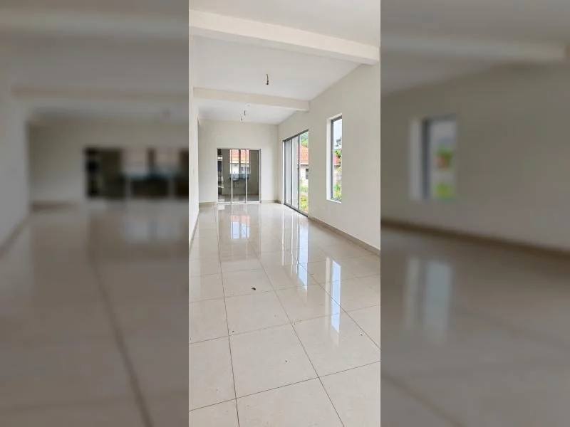Living features: white painted walls, large-format glossy ceramic tile flooring, tray ceiling, recessed ceiling beams, hanging light points, sliding glass door, floor-to-ceiling sliding glass door, large window, white window frames, natural light, open-plan long narrow layout, beige skirting boards, reflective tiled floor, view to exterior greenery; style: modern; view: garden.