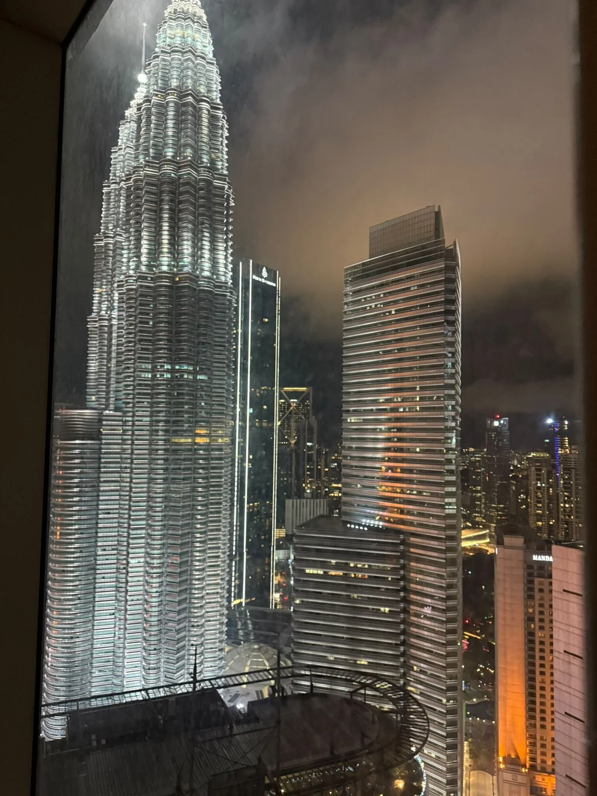 Exterior type: high-rise condominium; features: city skyline view, illuminated skyscrapers, glass curtain wall, modern architectural design, surrounded by urban landscape, nighttime lighting; style: modern.
