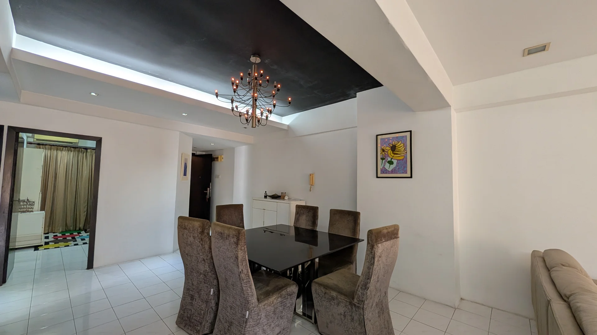 Dining features: black dining table, 6 upholstered dining chairs in grey, chandelier with multiple bulbs, white painted walls, white tiled flooring, recessed ceiling lights, decorative wall art, open layout to living area; style: modern. Room features: white painted walls, white tiled flooring.