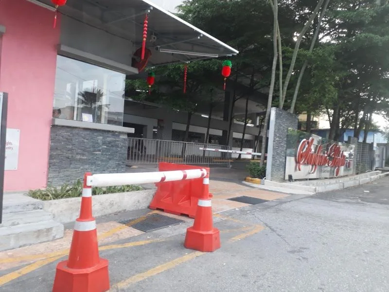 Exterior features: barrier gate, red and white traffic cones, stone cladding on wall, decorative red lanterns, paved driveway, fenced area, landscaped greenery; style: modern.
