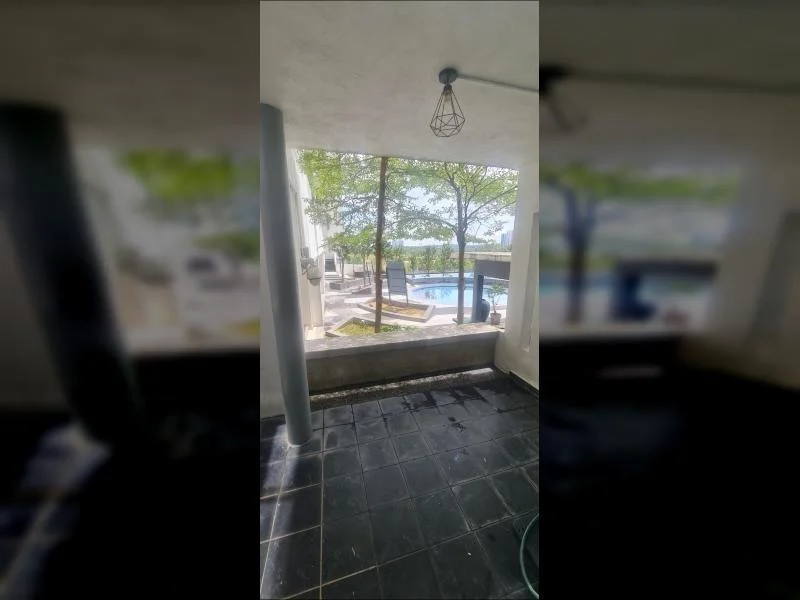 Room features: black tiled flooring, large window with view of pool, hanging pendant light, exposed concrete wall, outdoor view with trees, sliding glass door, patio area, poolside loungers visible; style: modern; view: pool.